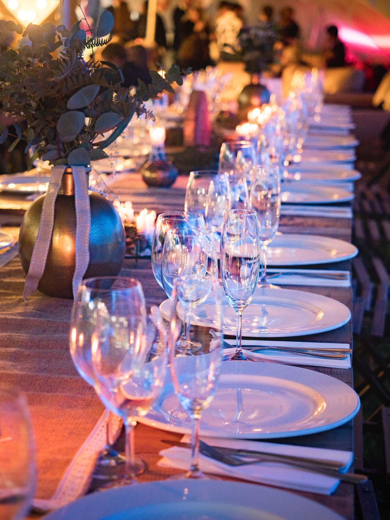 A long candlelit table of plates and glassware
