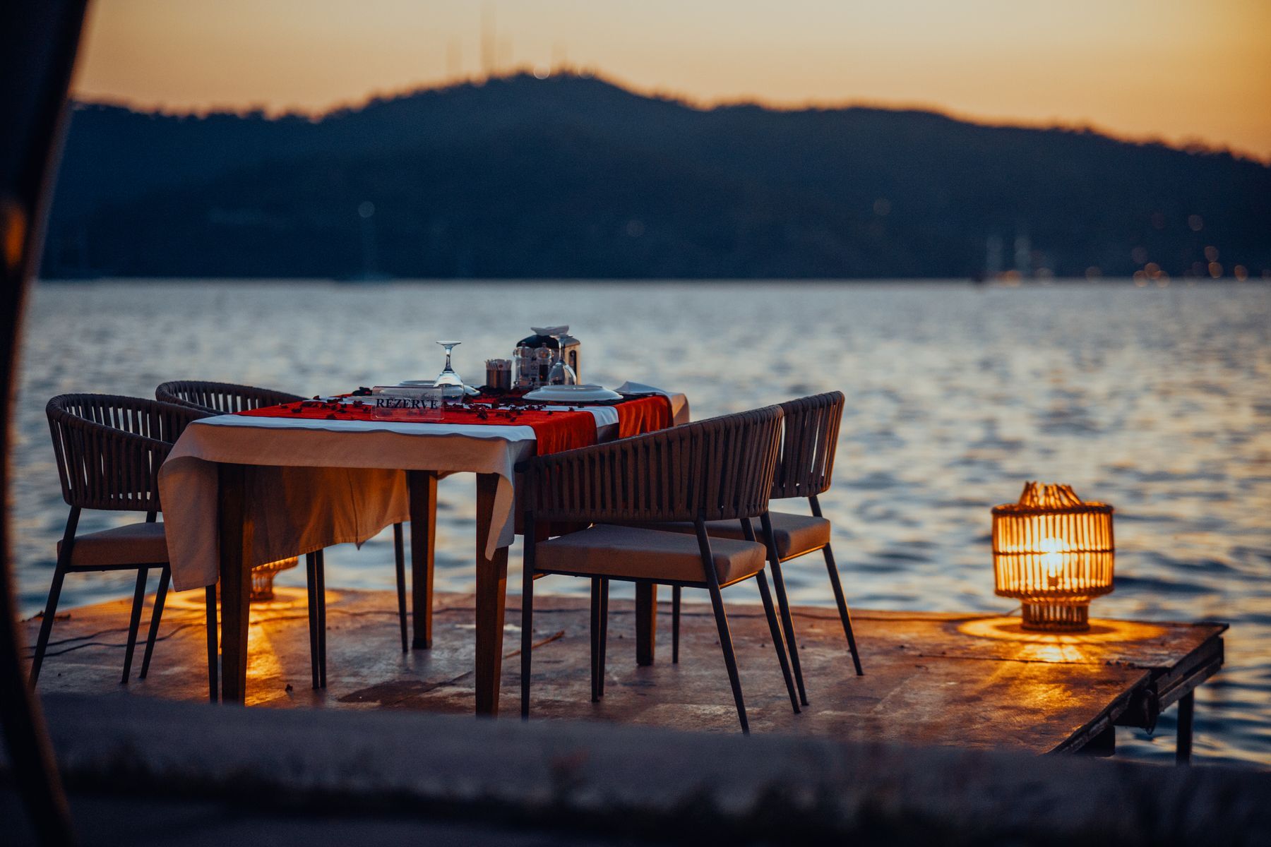 A dinner table set on a lakeside dock at dusk