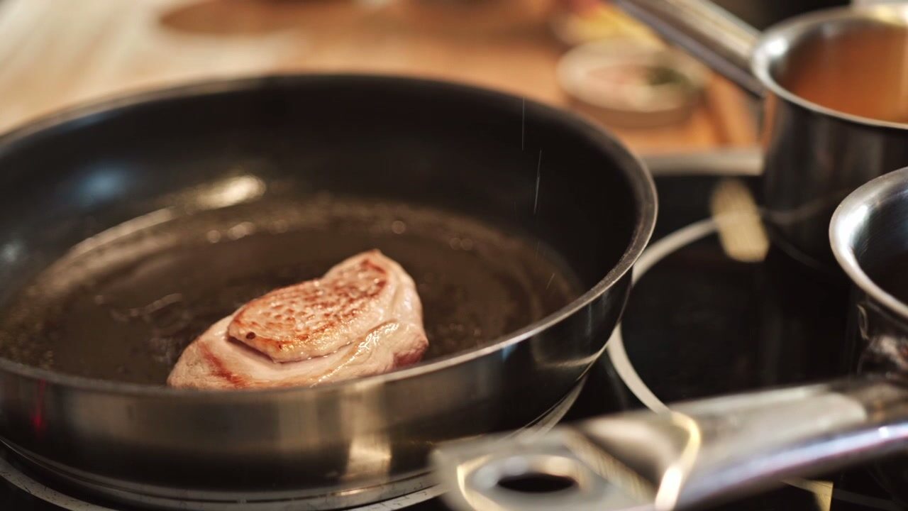 A steak searing in a hot pan