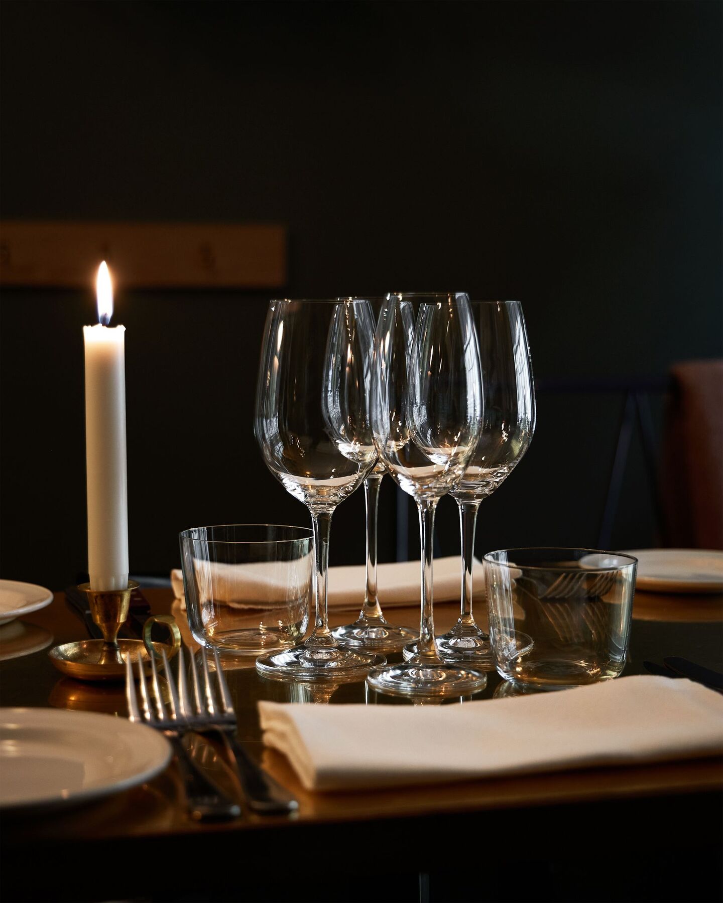 Wine glasses and a single candle on a set dinner table
